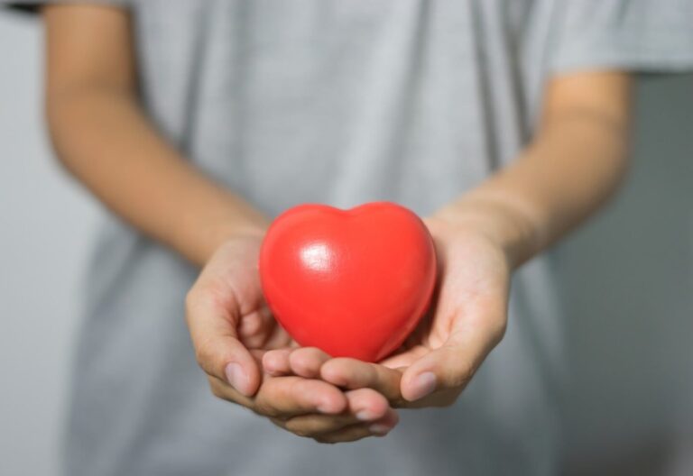 Variedad de alimentos saludables para el corazón: pescado, nueces, aceite de oliva y verduras en una tabla de madera.