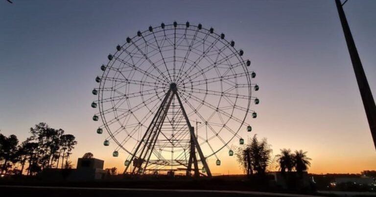 Fotografía que muestra la estructura colapsada de una rueda de la fortuna en un parque de diversiones de India, con servicios de emergencia en el lugar.
