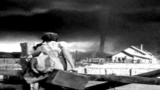 Escena de 'El Mago de Oz' mostrando el contraste entre el sepia de Kansas y los colores vibrantes de Oz.