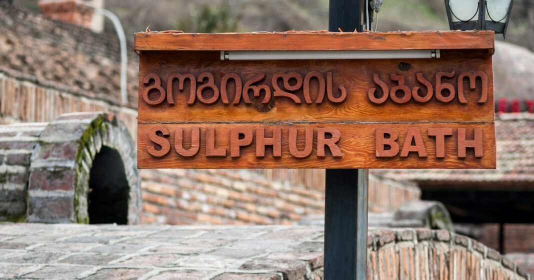 Ejemplo de escritura en alfabeto georgiano mkhedruli junto a un mapa de la región del Cáucaso.