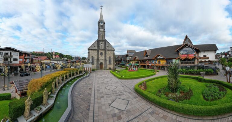 Vista de la arquitectura alpina y calles de Gramado, Brasil, con montañas de fondo.
