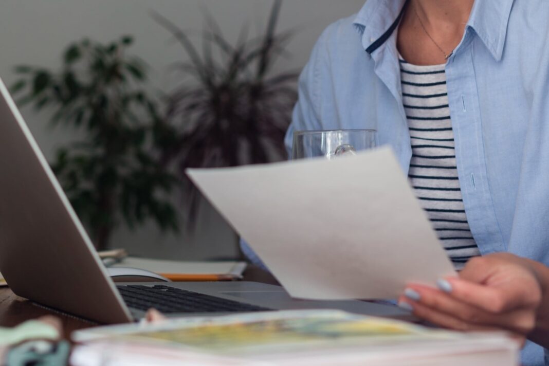 Persona revisando un recibo de sueldo en Argentina con lupa y calculadora.