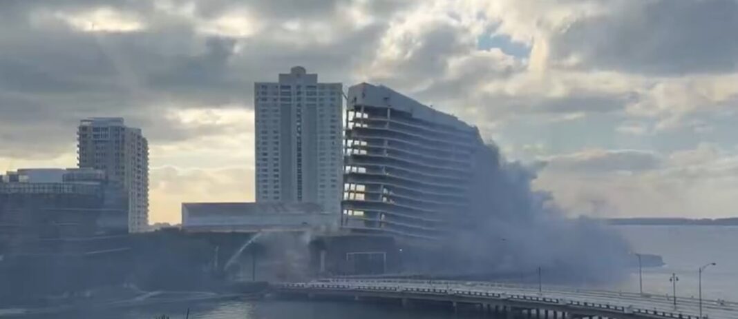 Momento de la implosión controlada del edificio del Hotel Mandarin Oriental de Miami, con una nube de polvo rodeada de rascacielos.
