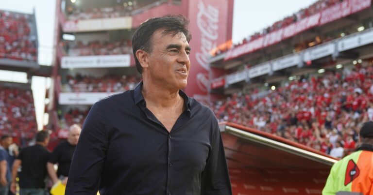 Escudos de Independiente y Racing Club, separados por un balón de fútbol, representando el clásico de Avellaneda.