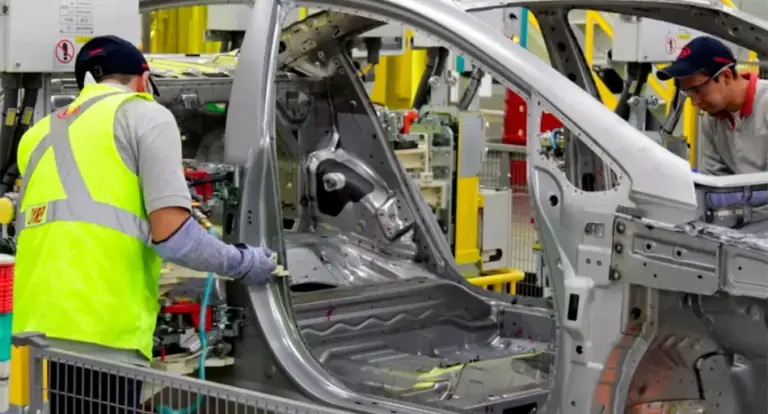 Fábrica de automóviles en Argentina con banderas nacionales y vehículos en línea de producción