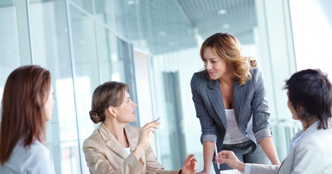Grupo diverso de jóvenes mujeres trabajando colaborativamente en laptops y pizarras durante un taller de tecnología.