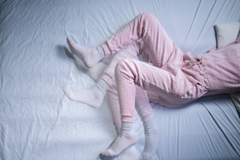 Persona estirando las piernas en la cama para aliviar el síndrome de piernas inquietas
