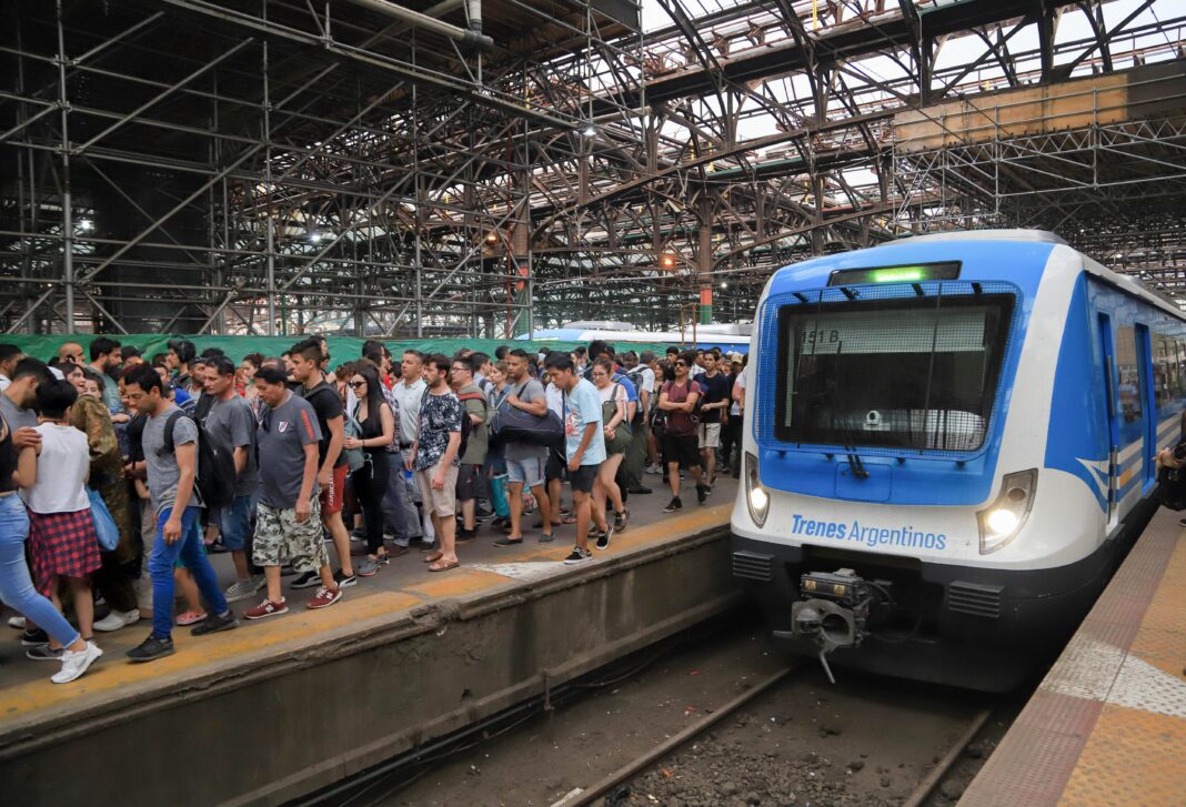 Andén de estación de trenes con pasajeros esperando y un tren detenido en Buenos Aires