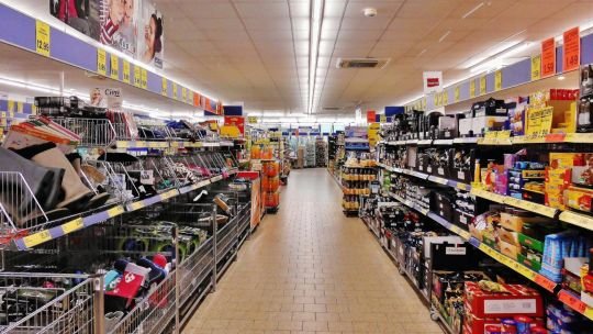Persona en supermercado revisando promociones en góndola
