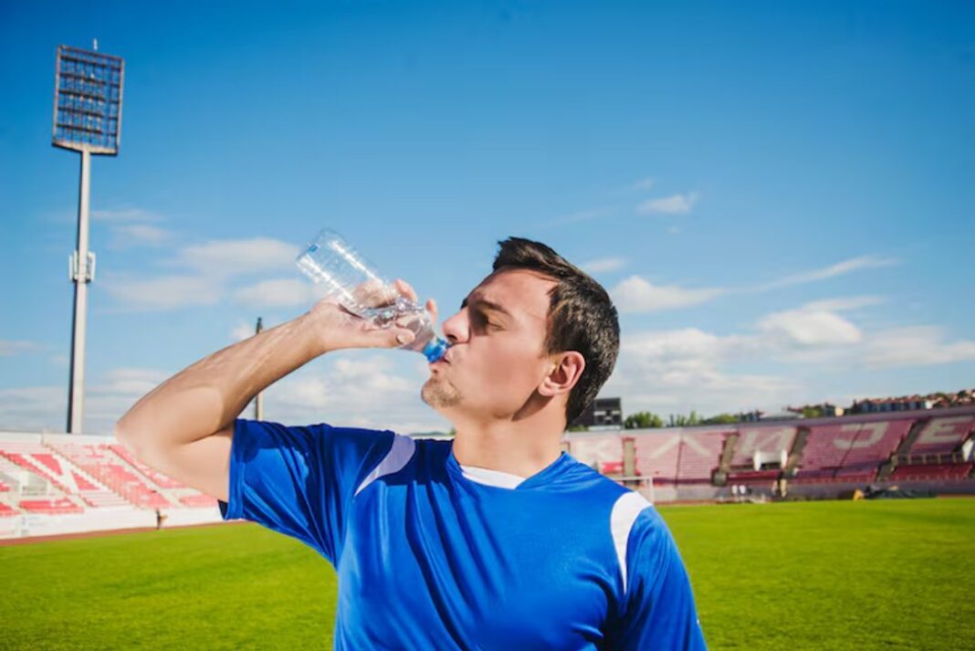 Persona bebiendo agua mientras mira un partido de fútbol en televisión
