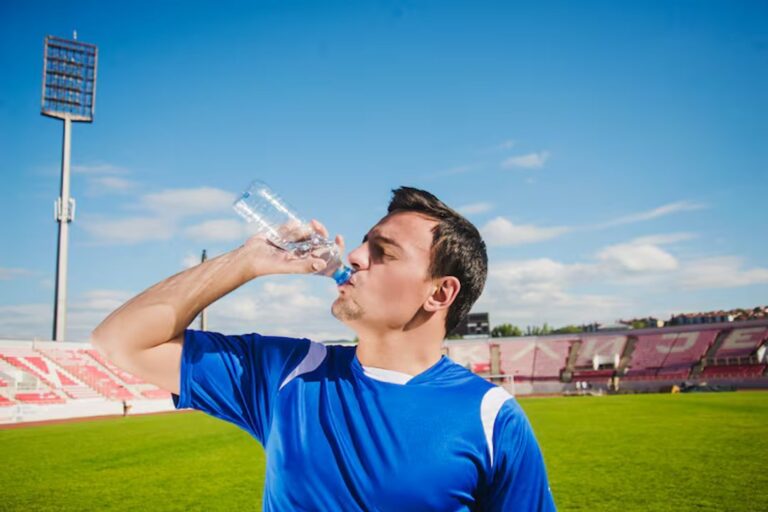 Persona bebiendo agua mientras mira un partido de fútbol en televisión