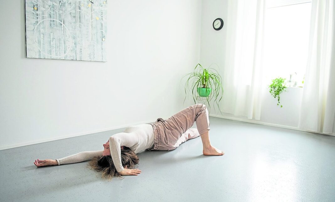 Persona realizando ejercicio del método Feldenkrais en el piso sobre una colchoneta