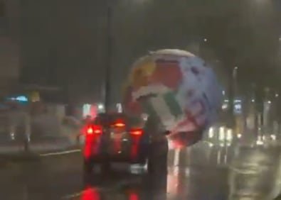Pelota inflable de gran tamaño rodando por una calle de San Salvador durante una tormenta
