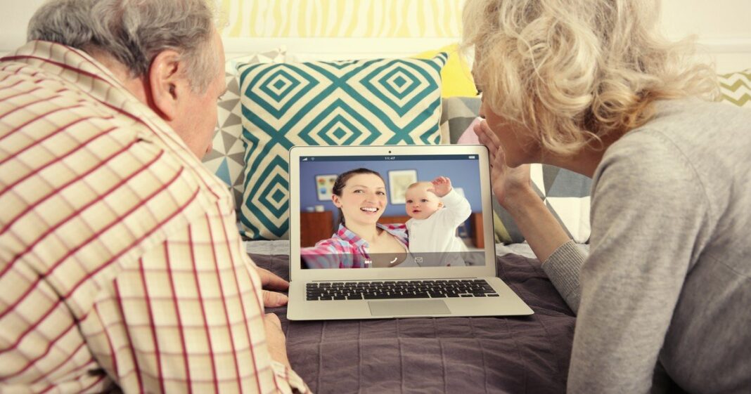 Abuelo sosteniendo un teléfono para hacer una videollamada con un nieto bebé