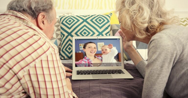 Abuelo sosteniendo un teléfono para hacer una videollamada con un nieto bebé