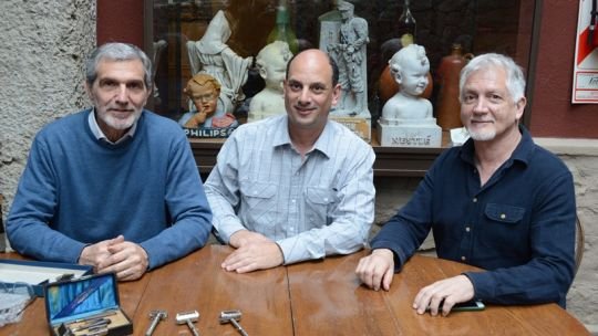 Colección de objetos antiguos de barbería y publicidad corpórea exhibidos en estanterías.