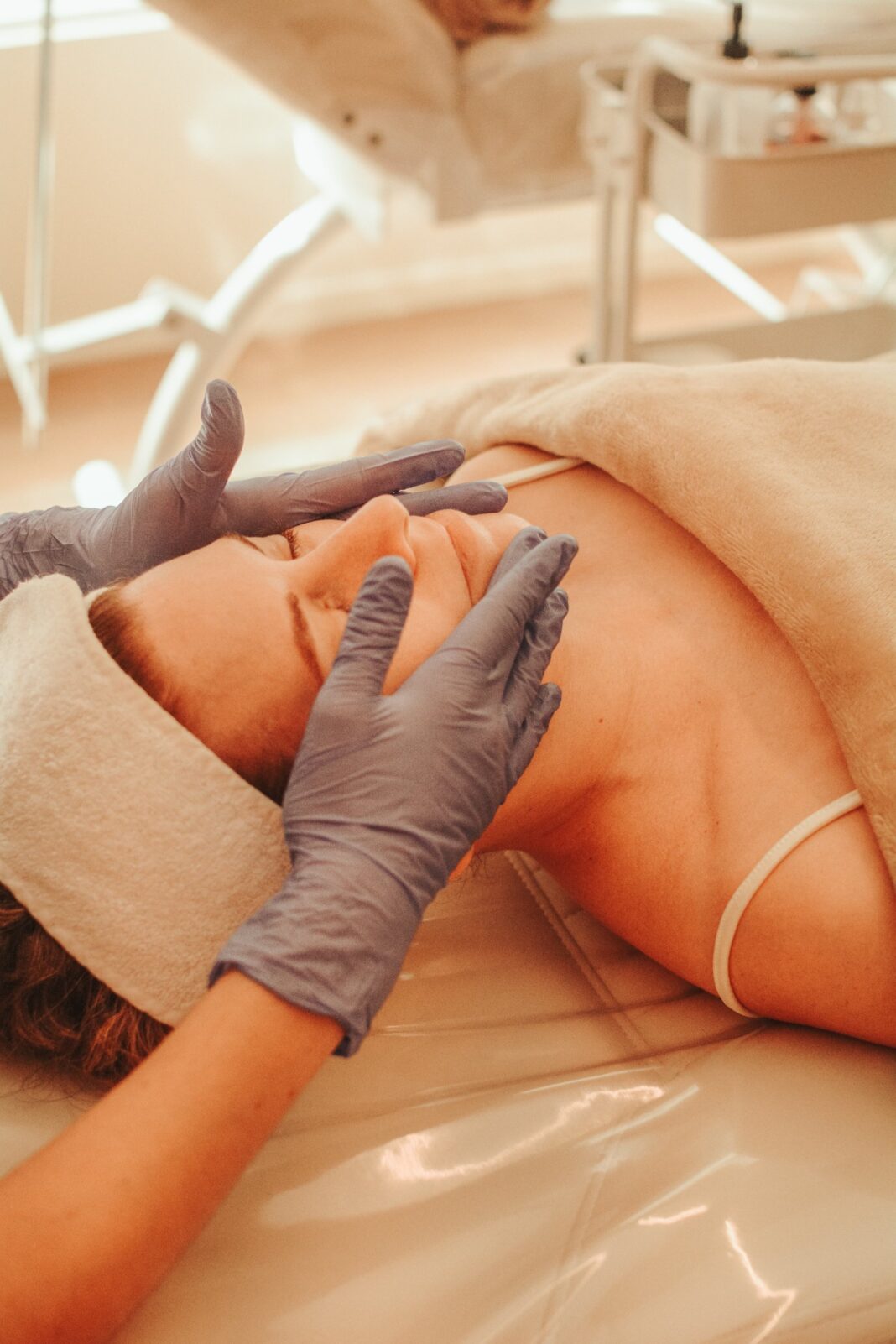 Mujer recibiendo un masaje facial y capilar en una camilla