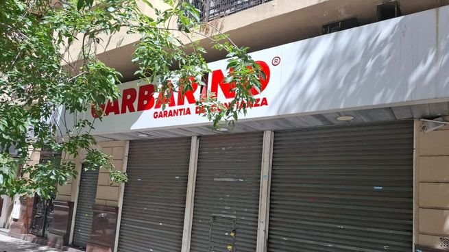 Frente de un local de Garbarino con persianas metálicas bajas y cartelería de la marca