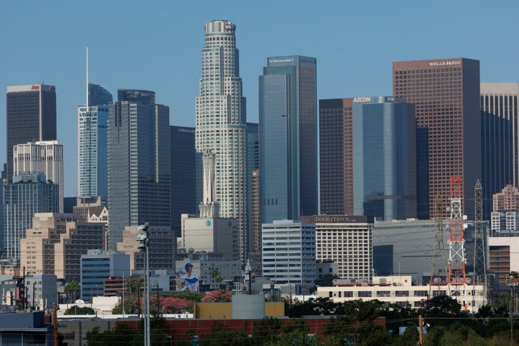 Vista de una calle residencial en Los Ángeles con viviendas y carteles de venta