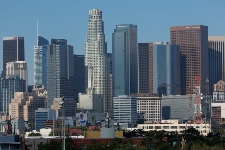 Vista de una calle residencial en Los Ángeles con viviendas y carteles de venta